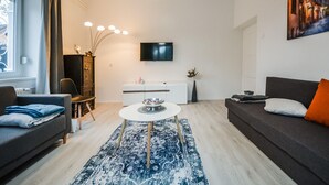Una sala de estar moderna con un sofá, una mesa de comedor y un televisor montado en la pared.