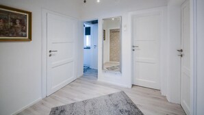 Un pasillo con puertas blancas, un cuadro enmarcado a la izquierda y una alfombra gris en el suelo.