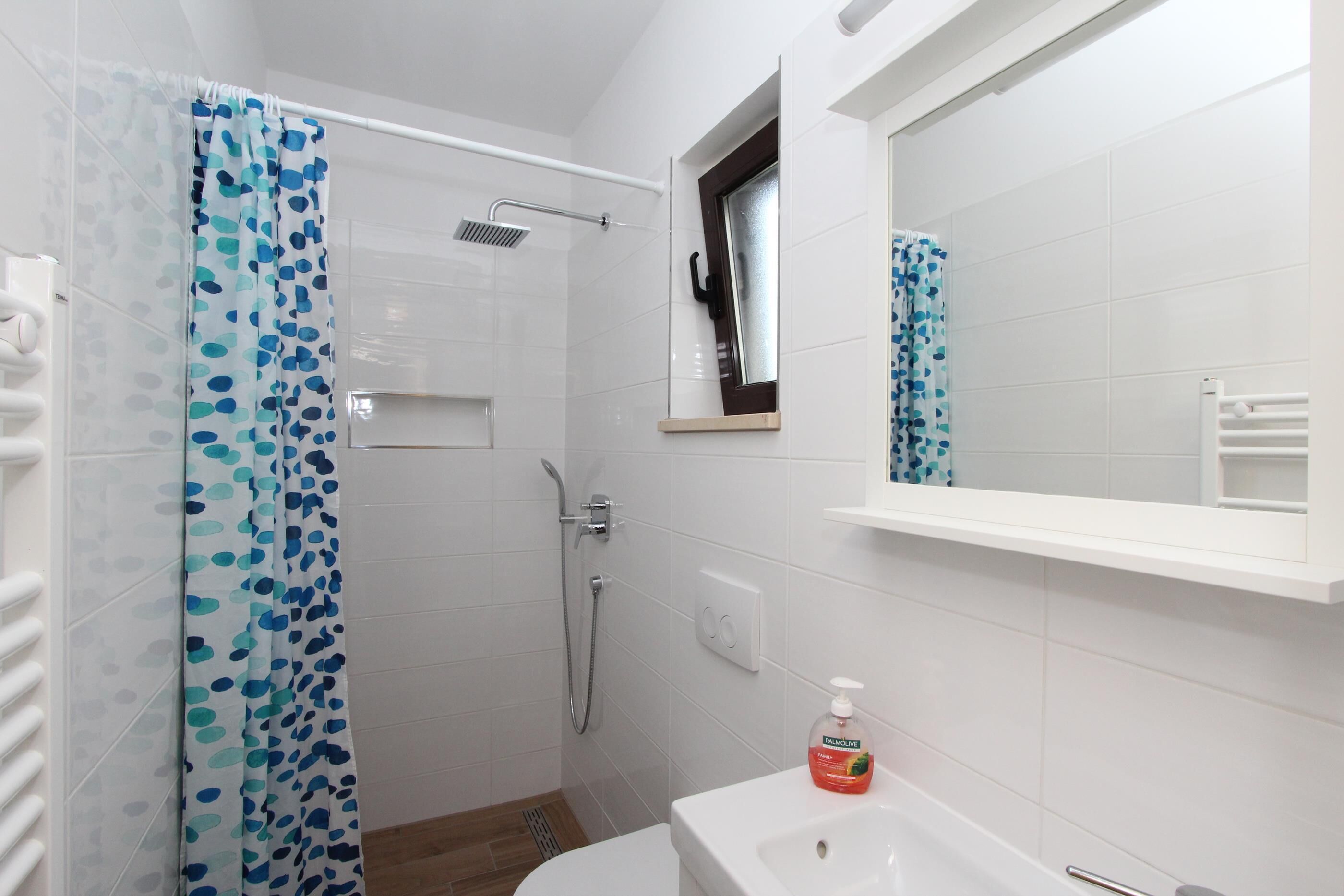 A bathroom with a shower, a toilet, a sink, and a mirror.