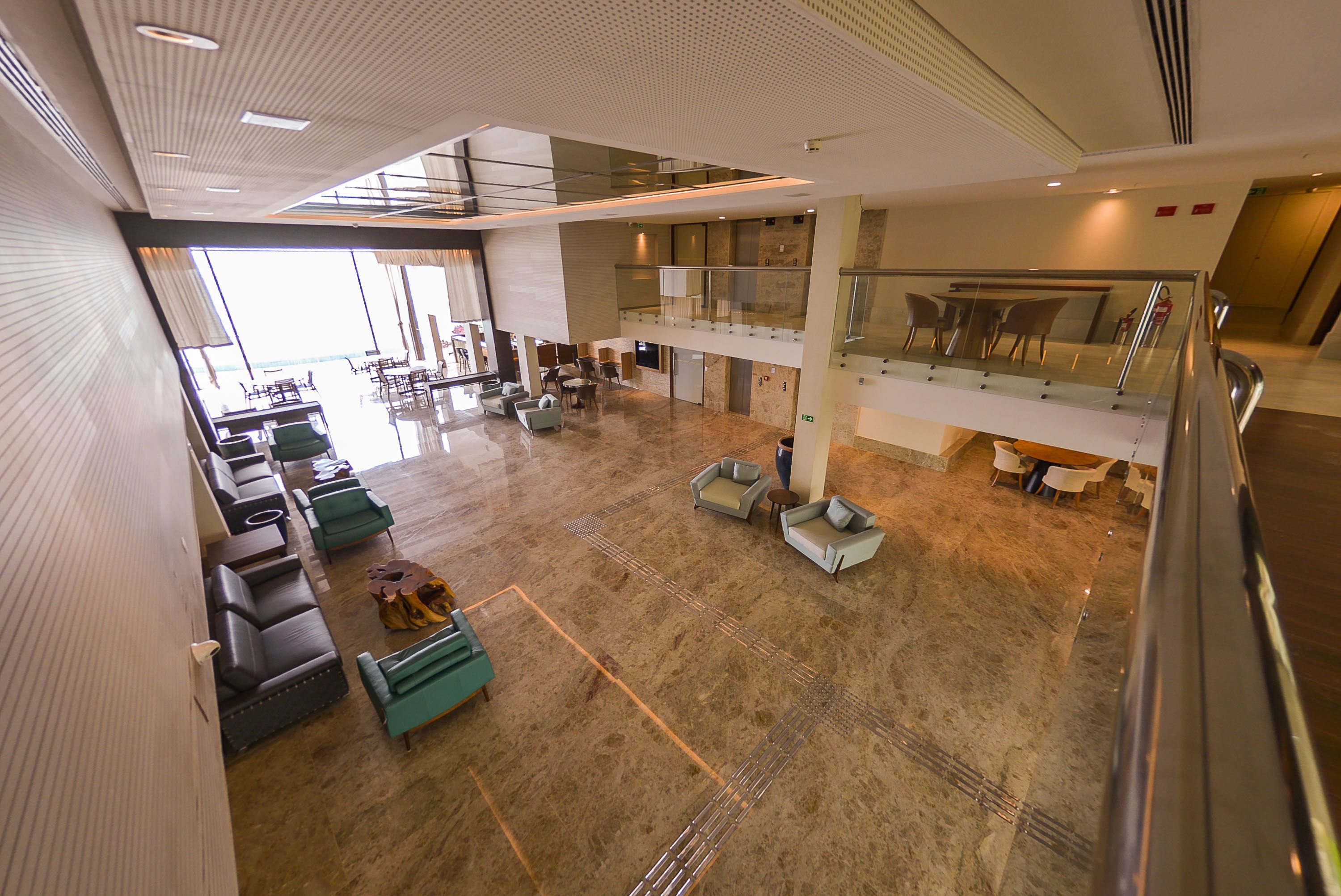 Un hall d’entrée spacieux, doté de plusieurs espaces de détente, d’une rambarde en verre et d’un plafond haut.