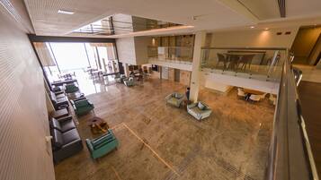 Un hall d’entrée spacieux, doté de plusieurs espaces de détente, d’une rambarde en verre et d’un plafond haut.