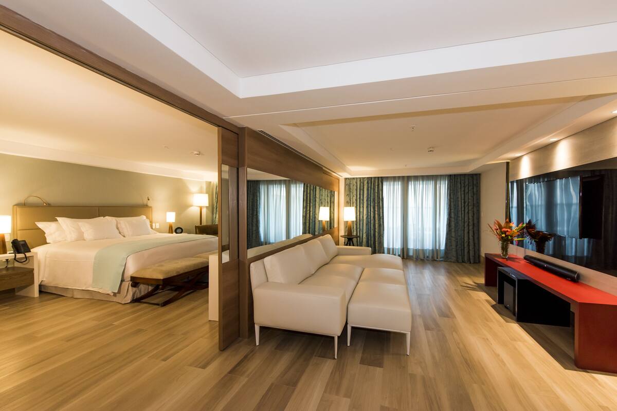 Una habitación de hotel con cama, sofá, escritorio y televisión.