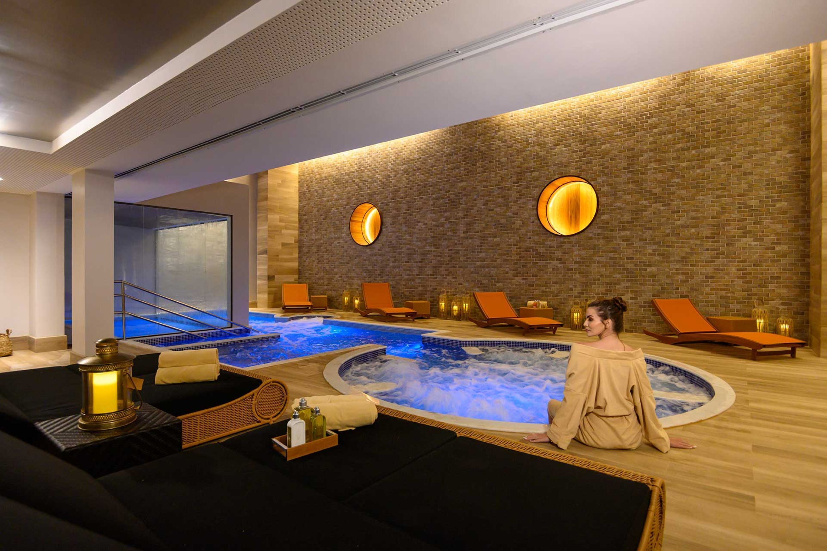 Zona de spa con un jacuzzi, sillones reclinables y una camilla de masaje.