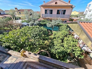 A residential area with a house featuring a balcony, a swimming pool, and well-maintained gardens.