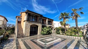 A two-story house with a stone facade, a balcony, and a tiled courtyard. - Apartments Marlina (Rovinj)