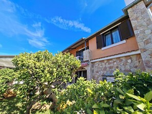 A two-story building with stone and stucco exterior, a balcony, and lush greenery in front. - Apartments Marlina (Rovinj)