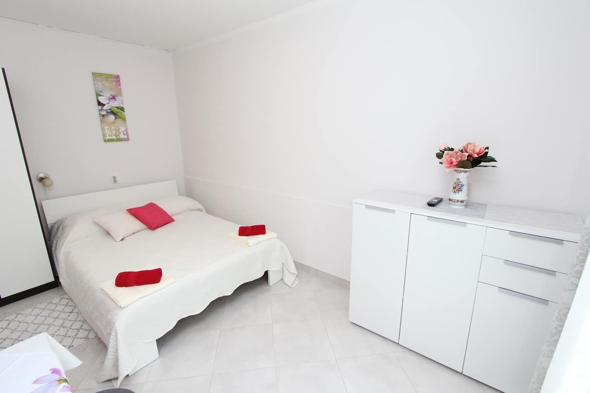 A bedroom with a bed, a white dresser, and a vase with flowers.