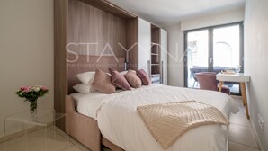 A modern bedroom with a large bed, a desk, and a window. - Boutique 2 bedroom apartment VRBO (Nice)