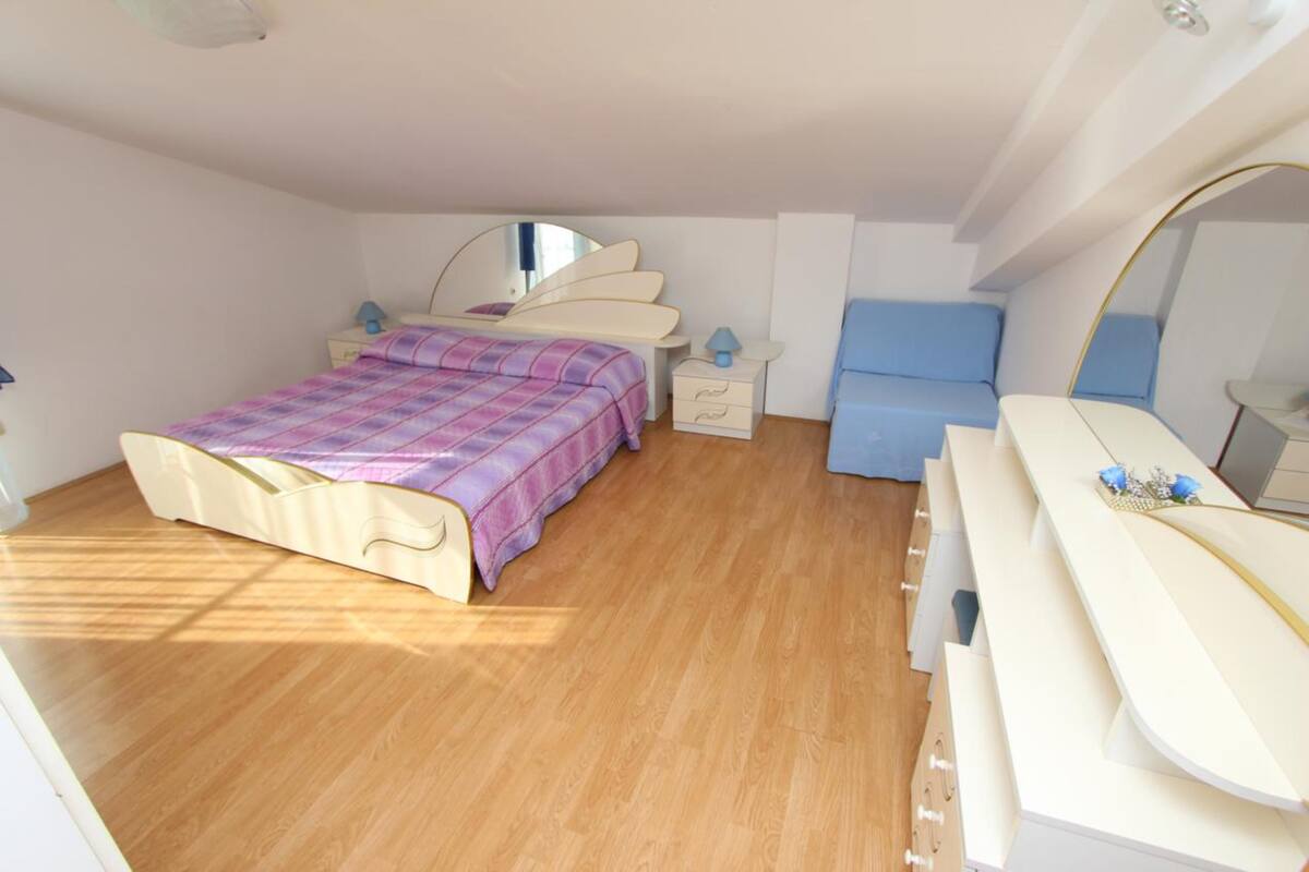 Une chambre à coucher avec un lit, une commode, un miroir et une chaise bleue.
