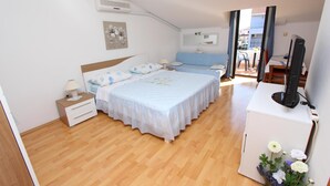Een slaapkamer met een bed, nachtkastjes, een bureau met stoel, een televisie en een raam met gordijnen.