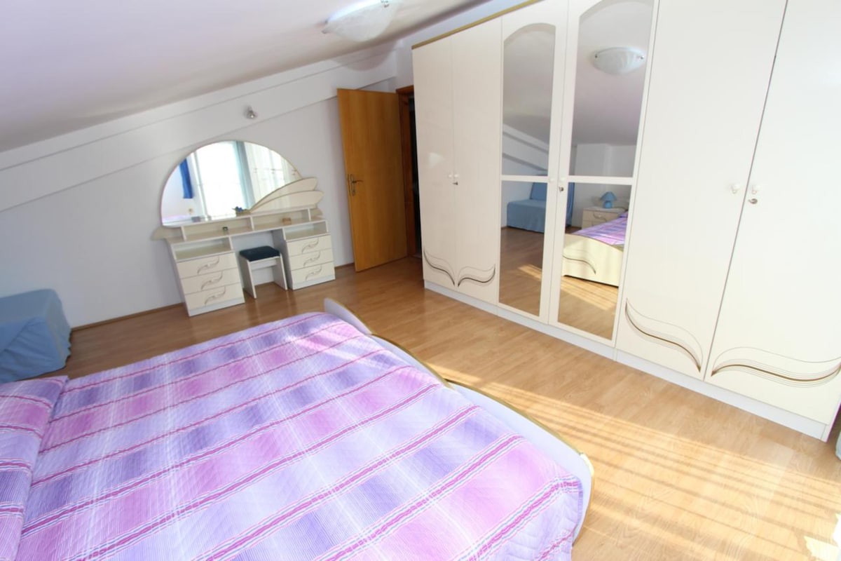 Um quarto com cama, penteadeira, espelho e guarda-roupa.
