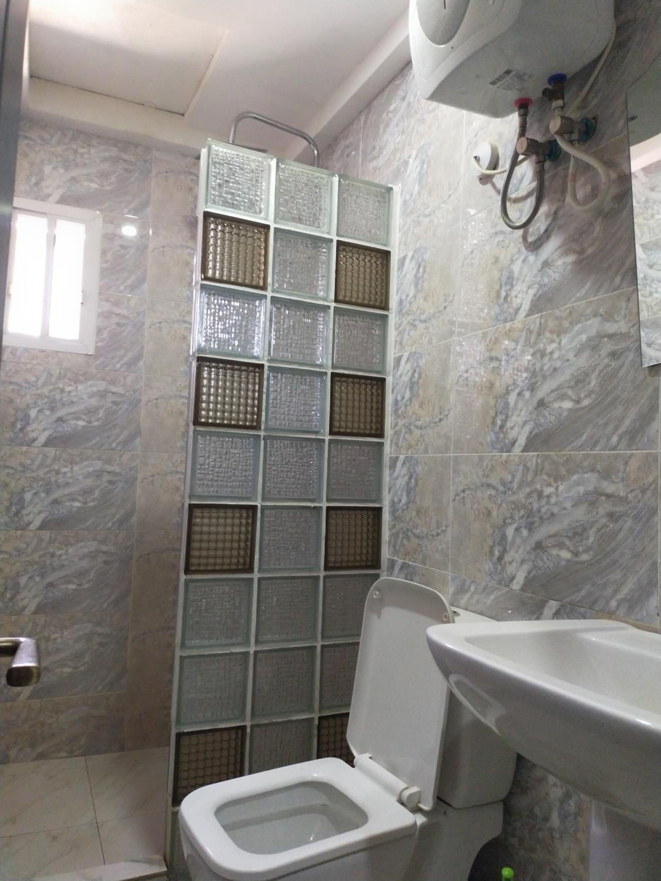 Un baño con inodoro, lavamanos y ducha con puerta de vidrio.