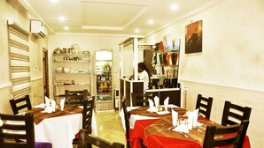 A restaurant with tables set for dining, a bar area, and shelves stocked with bottles. - BoardWalk Hotels Zone 5 (Abuja)