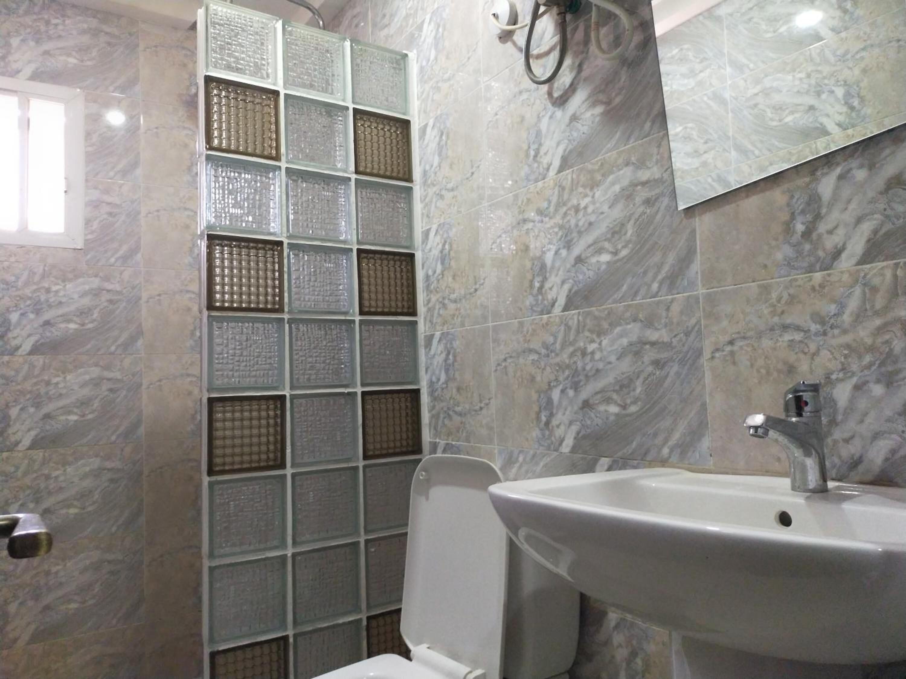 Une salle de bain avec un lavabo blanc, des toilettes et une douche dotée d’une porte en verre.