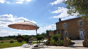 A stone building with a pool and lounge chairs.
