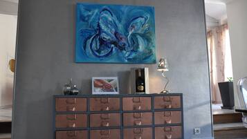 A modern lobby with a blue abstract painting, a metal cabinet with drawers, a framed picture, and a bottle of champagne.
