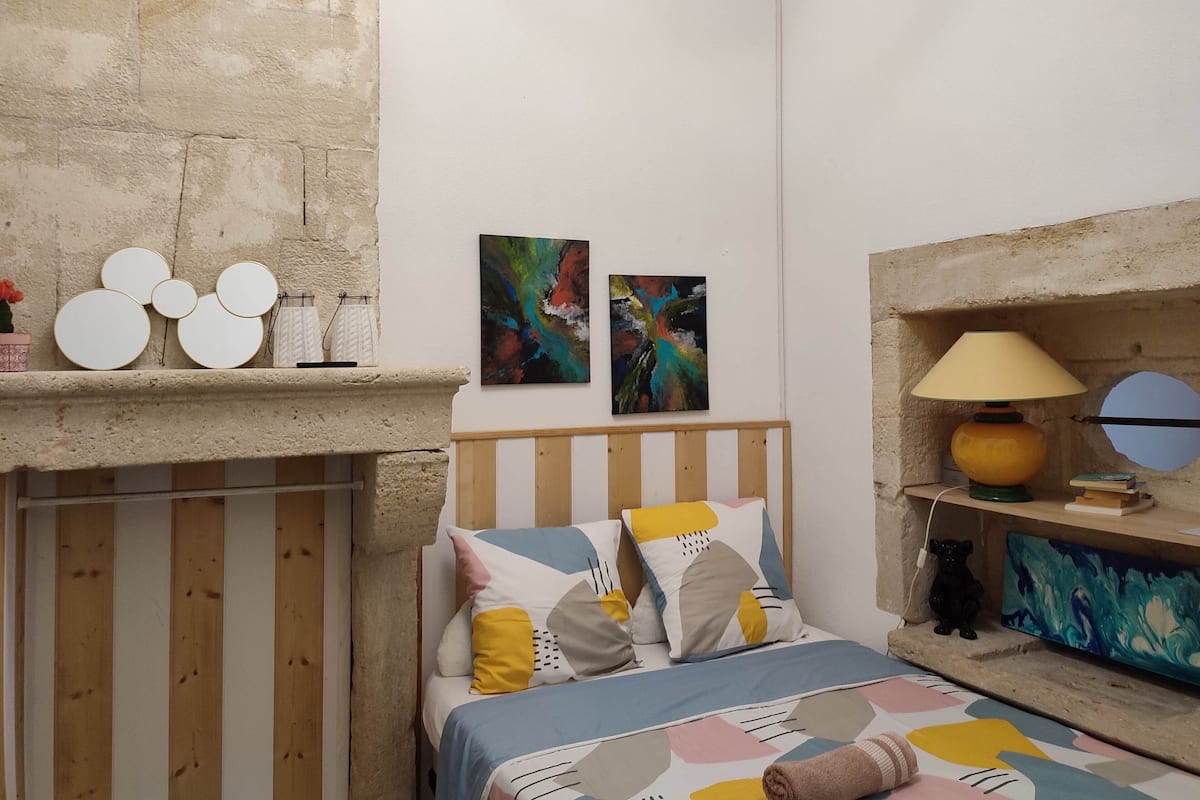 Une chambre à coucher avec un lit en bois, une table de chevet avec une lampe et des œuvres d’art abstraites accrochées au mur.