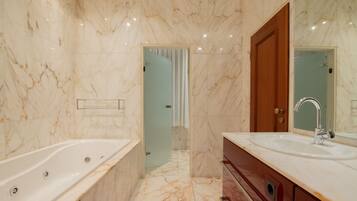 A modern bathroom with a marble floor, a large bathtub, a sink with a mirror, and a wooden cabinet.