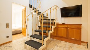 Un escalier au design moderne, un téléviseur à écran plat fixé au mur et un meuble en bois.