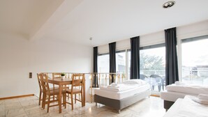 Une chambre d’hôtel moderne dotée d’un coin repas, d’un lit et de grandes fenêtres.