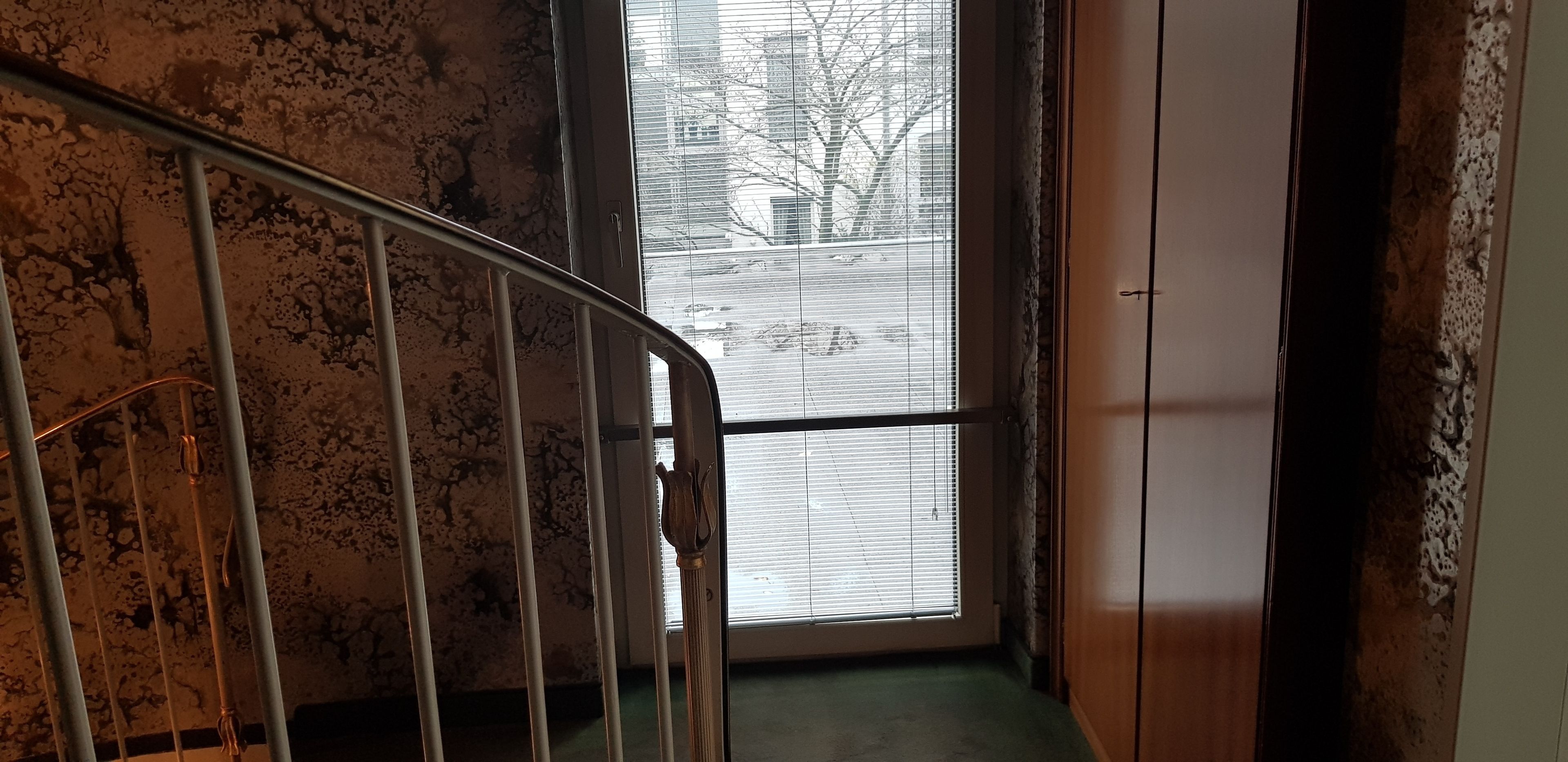 A staircase with a metal railing leading to a room with a large window.