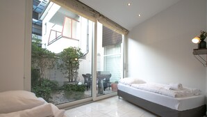 Une chambre moderne dotée d’une grande porte-fenêtre coulissante donnant sur un balcon agrémenté de plantes et d’une table.