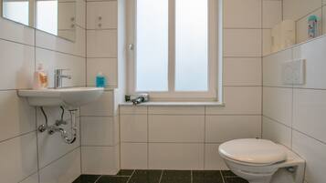 Un bagno con lavandino bianco, uno specchio, una finestra e un water.