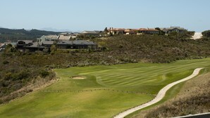 A golf course with a winding path, surrounded by houses on a hillside. - Villa 10 (Knysna)