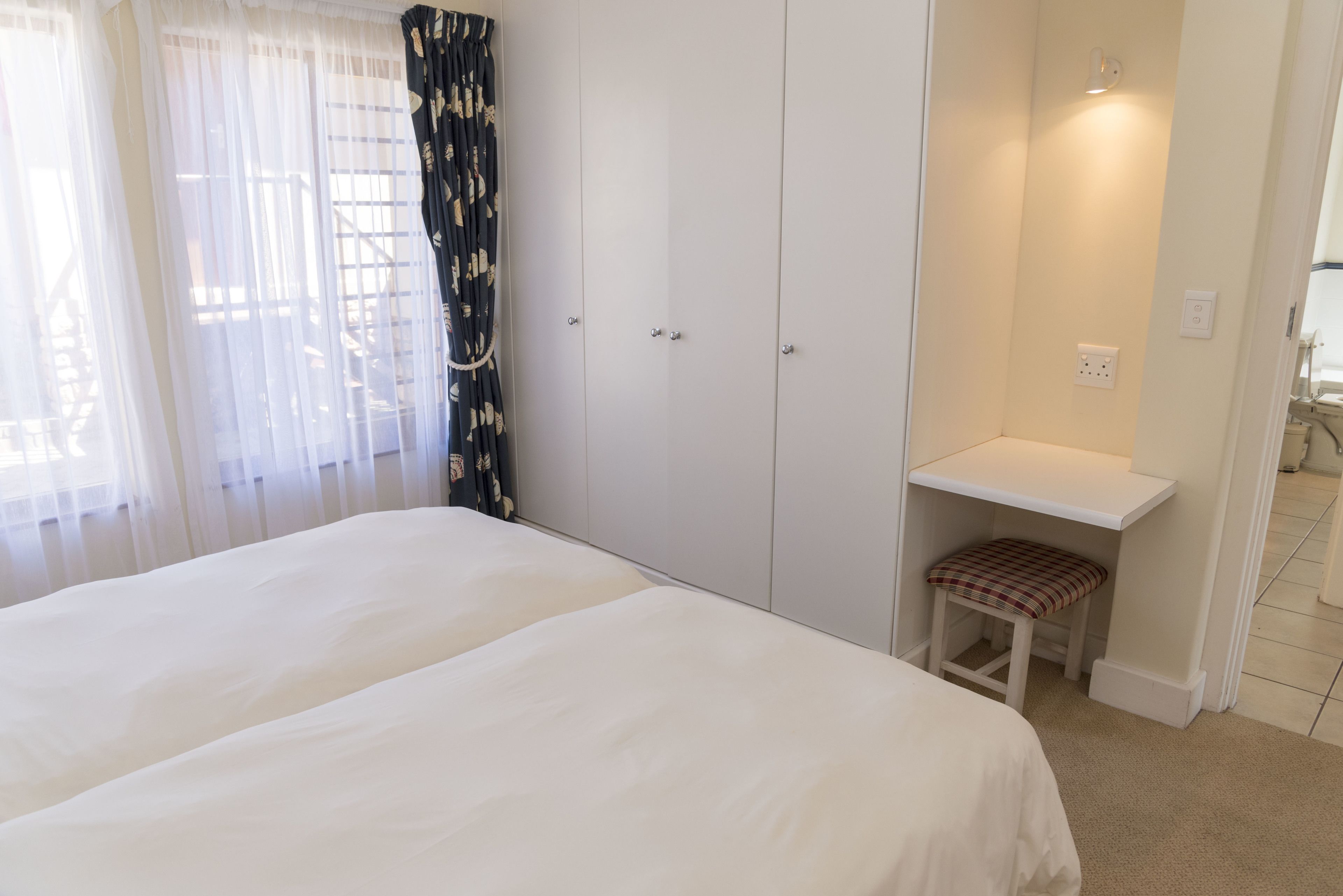 A bedroom with a large bed, a desk with a chair, and a wardrobe.