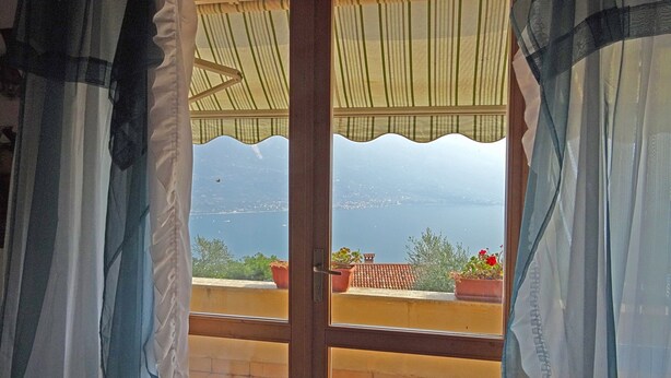 A view from a window with a wooden frame and a view of a body of water and distant land. - Holideal Villa Cinzia (Solofra)