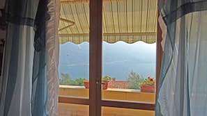 Blick aus einem Fenster mit Holzrahmen auf ein Gewässer und entfernte Landschaft.