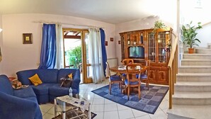 A living room with a sofa, a coffee table, and a TV. There is a staircase leading to another level. - Holideal Villa Cinzia (Solofra)
