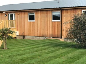 A wooden building with two windows and a covered porch. - Godshill Park Barn (Ventnor)