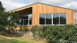 A modern building with a wooden facade, large windows, and a covered entrance. - Godshill Park Barn (Ventnor)