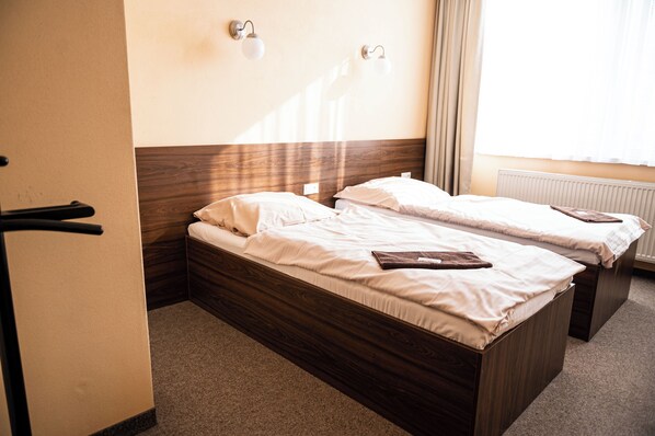Una habitación de hotel con dos camas de madera, un radiador y una puerta con manija.