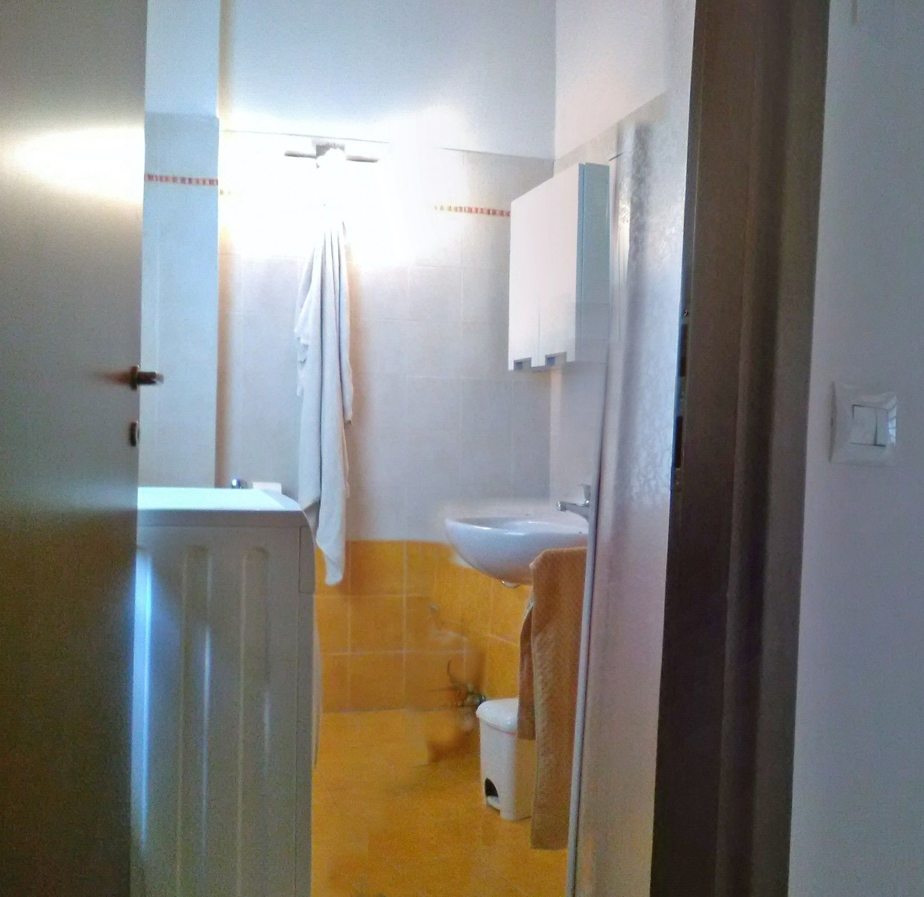 Un bagno piccolo con il water bianco, un lavandino e uno specchio sopra il lavandino.