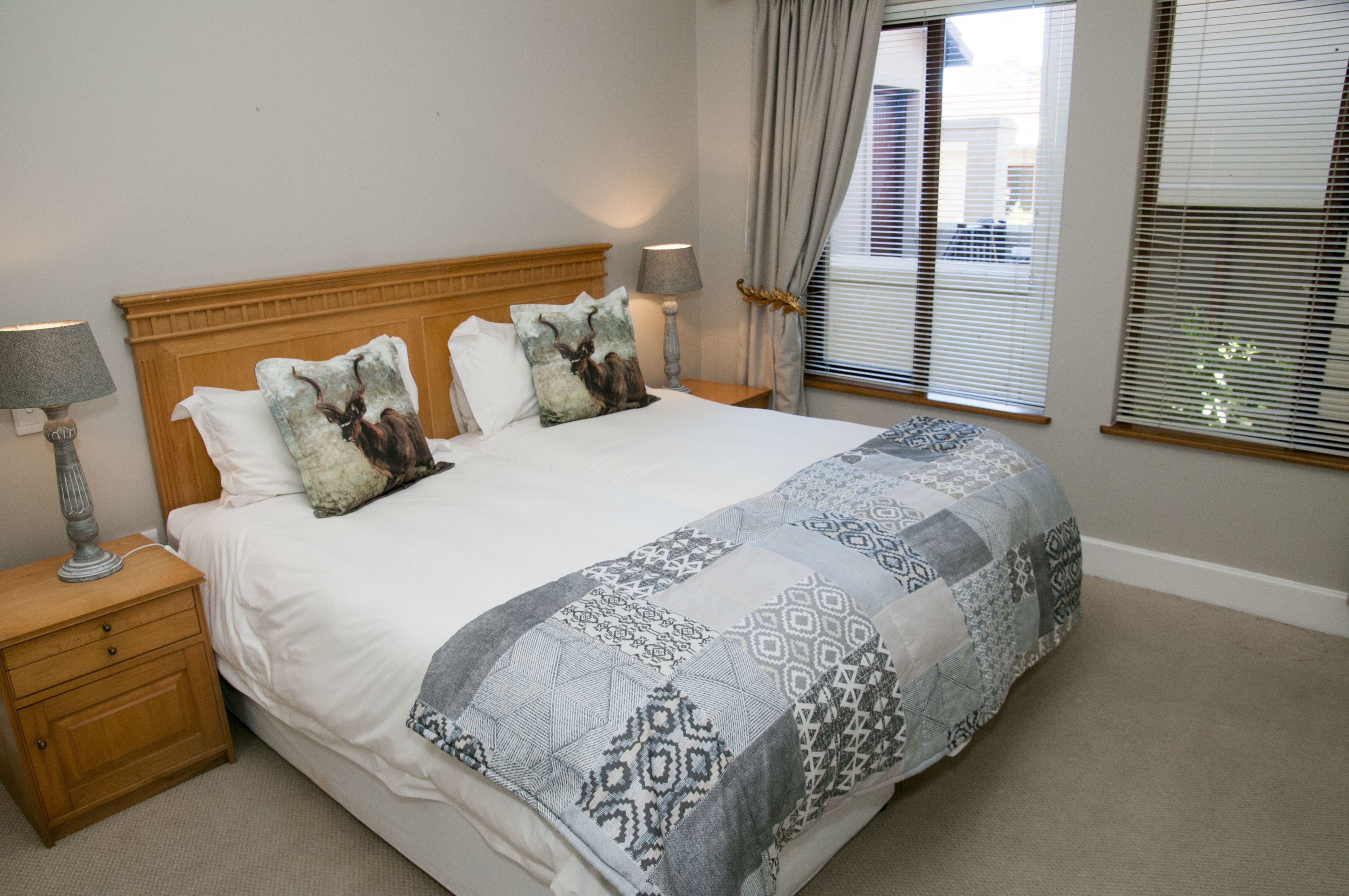 A neatly made bed with patterned bedding, a wooden headboard, and two bedside lamps.