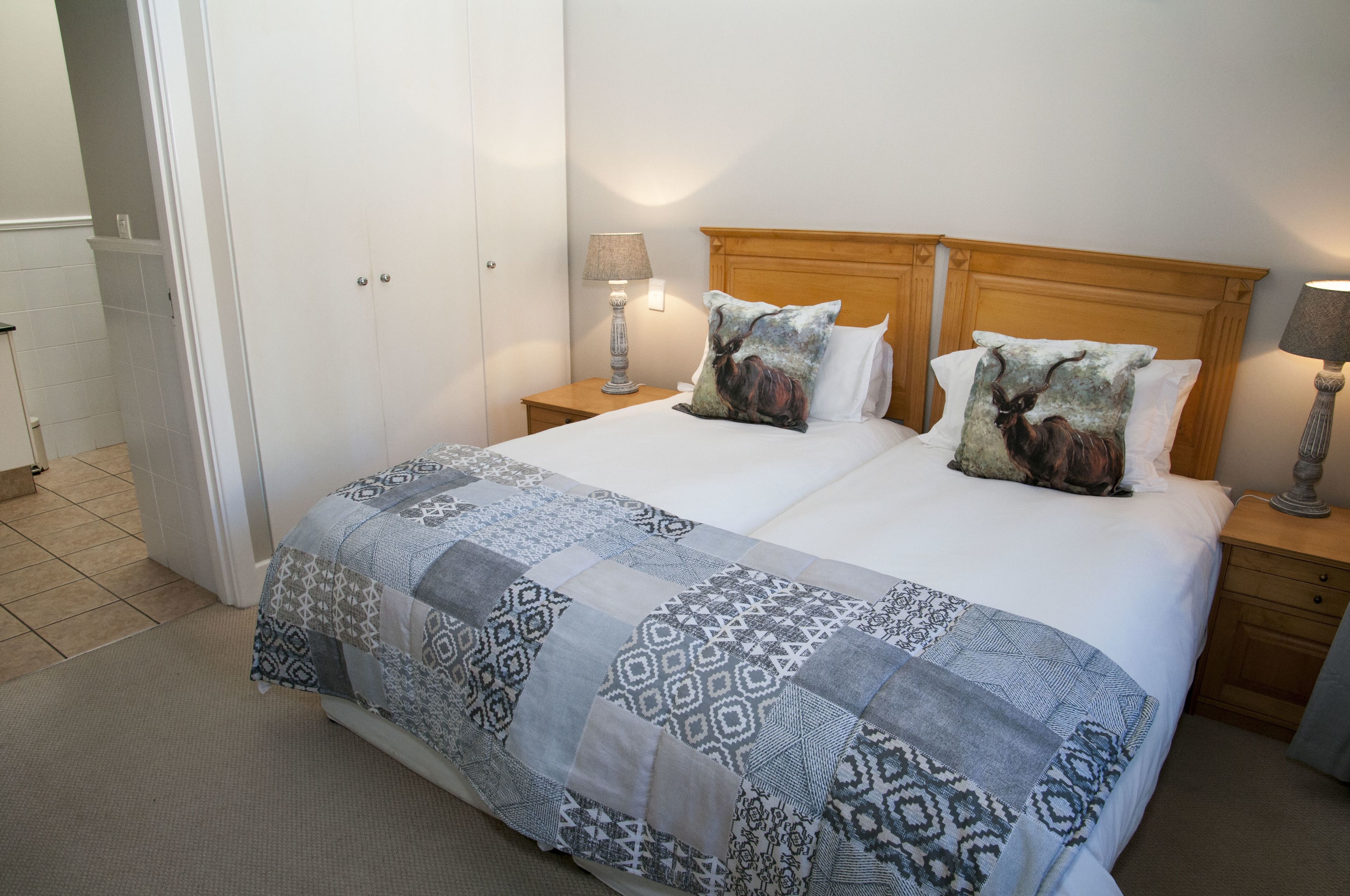 A neatly made bed with patterned bedding, two bedside lamps, and a wooden headboard.
