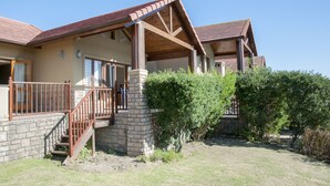 A two-story house with a covered porch, a stone staircase, and a well-maintained garden. - Villa 14 (Knysna)