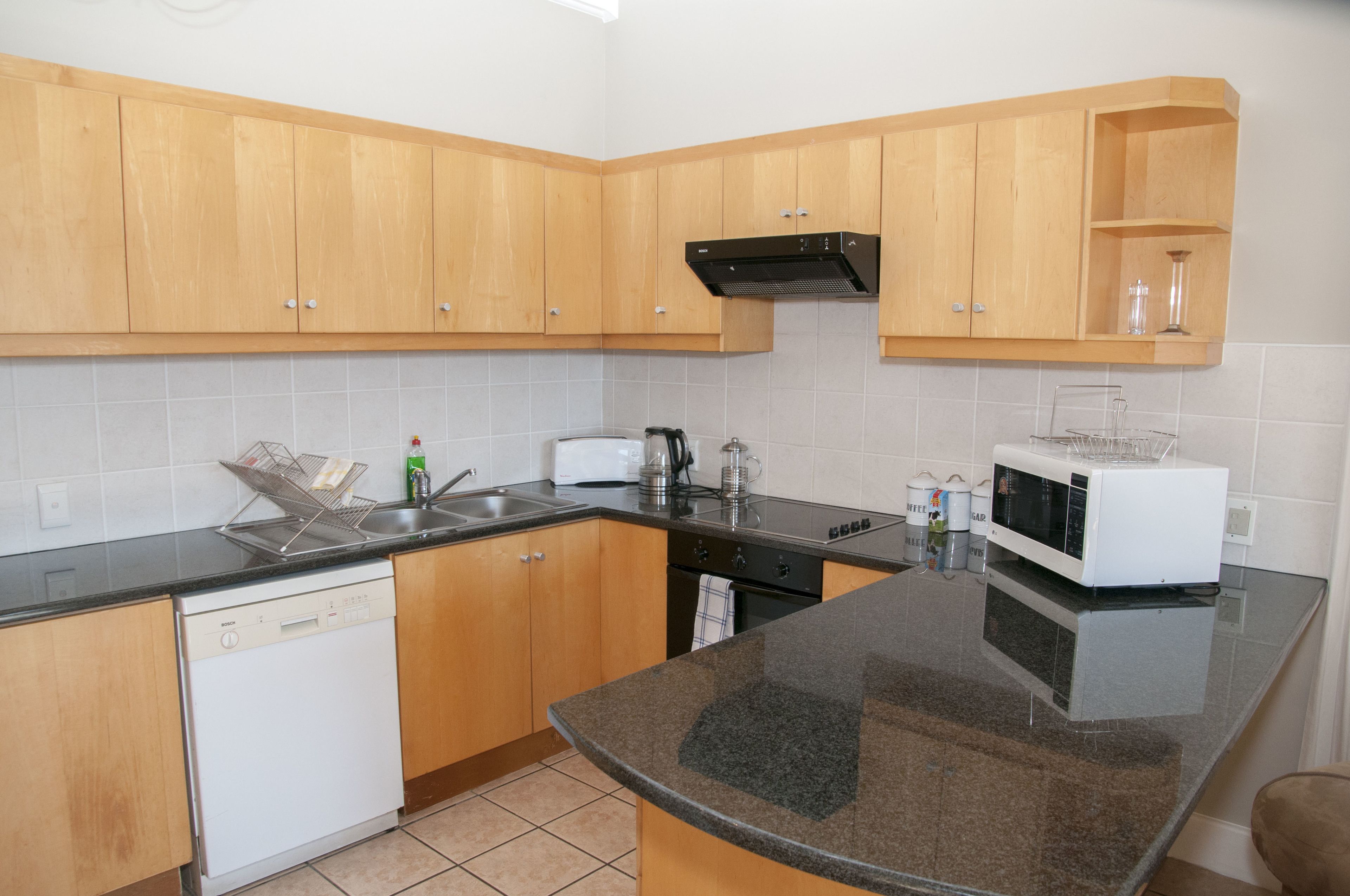 A kitchen with wooden cabinets, a dishwasher, a microwave, and a sink.