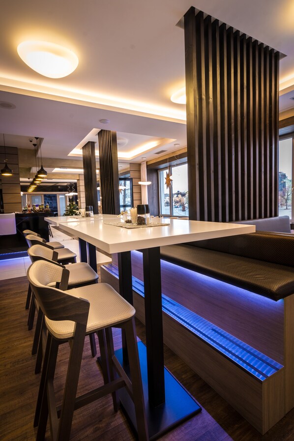 Una cocina moderna con una isla central, taburetes de bar y una zona de estar con vistas a la ciudad.