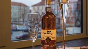 A bottle of Caterling wine, a candle, and a glass on a table with a view of a cityscape and a tower in the background.