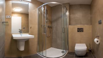 A modern bathroom with a glass-enclosed shower, a sink, and a toilet.