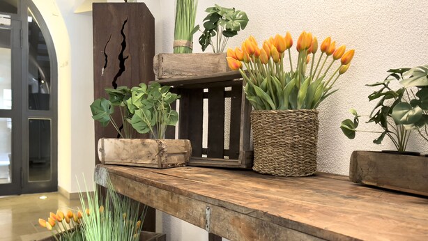 A wooden table with various potted plants and flowers.