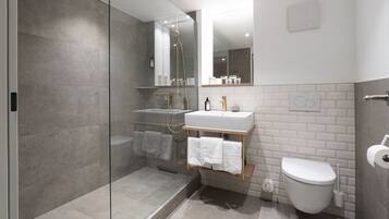 A modern bathroom with a glass-enclosed shower, a white sink, and a toilet.