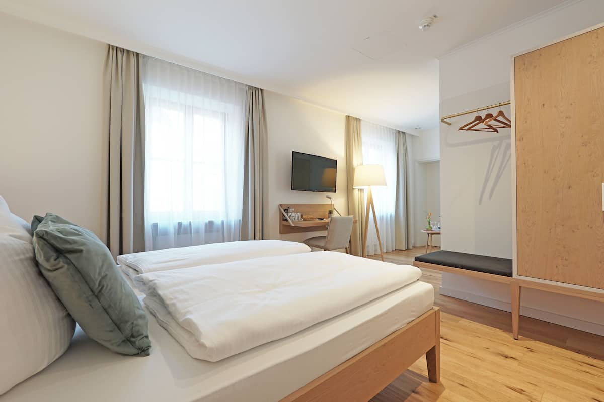 A hotel room with a large bed, a desk, a TV, and a wardrobe.