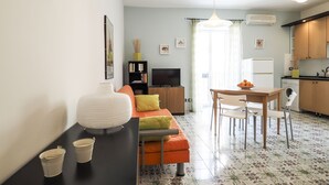 Un espace de vie compact comprenant un canapé, une table à manger et un coin cuisine.