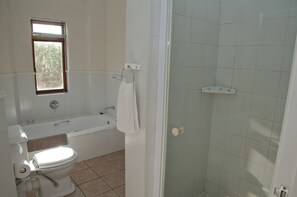 A bathroom with a toilet, bathtub, and shower. - Villa 16 (Knysna)