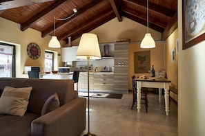 Un salon confortable avec un canapé et une table basse, une cuisine équipée d’appareils modernes et un coin repas avec une table et des chaises.