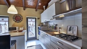 A modern kitchen with a central island, stainless steel appliances, and a large window.